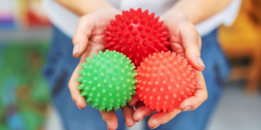 A child's hands cupped around three spiky textured sensory balls