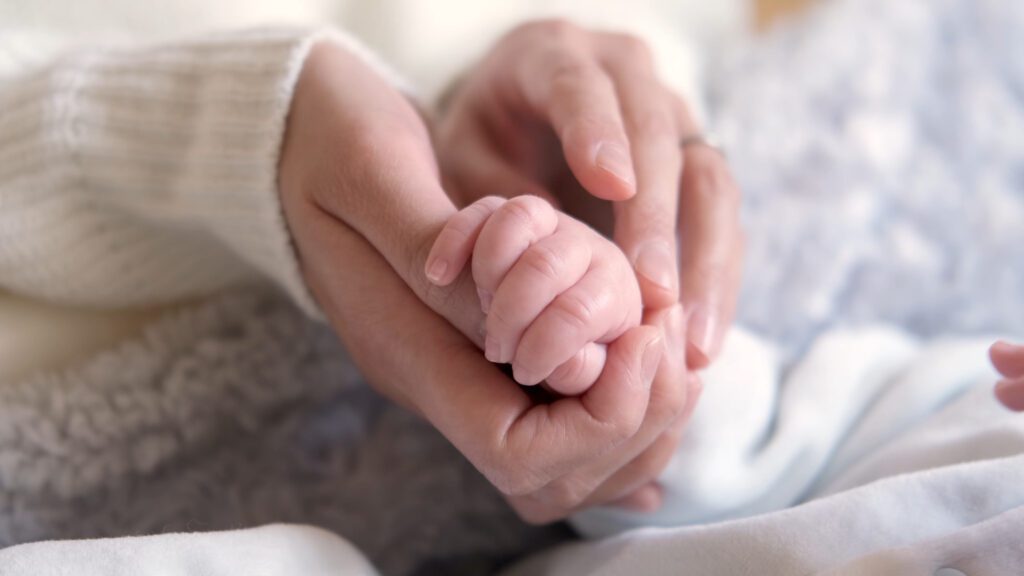 Young,Mother,Holding,Baby's,Hand