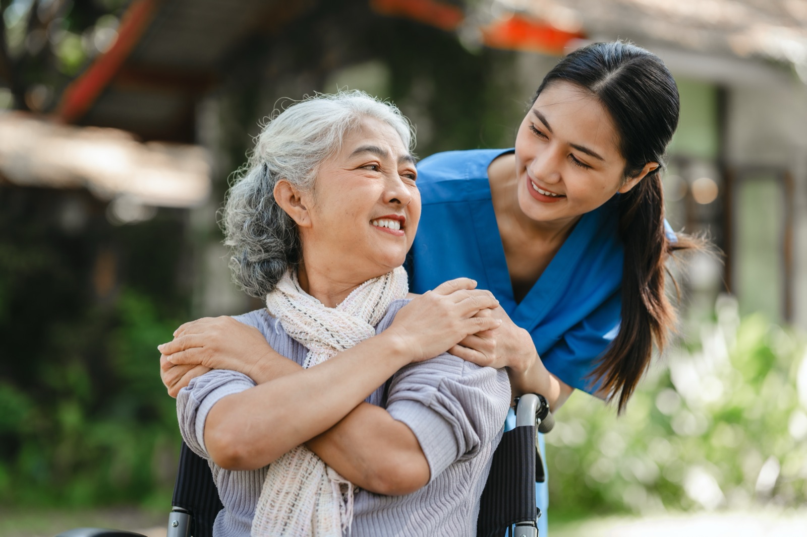 A clinician sitting with a patient, hands clasped over her shoulders, in an unhurried conversation outdoors.
