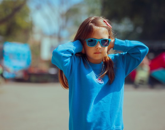 A girl outdoors covering both ears with her hands