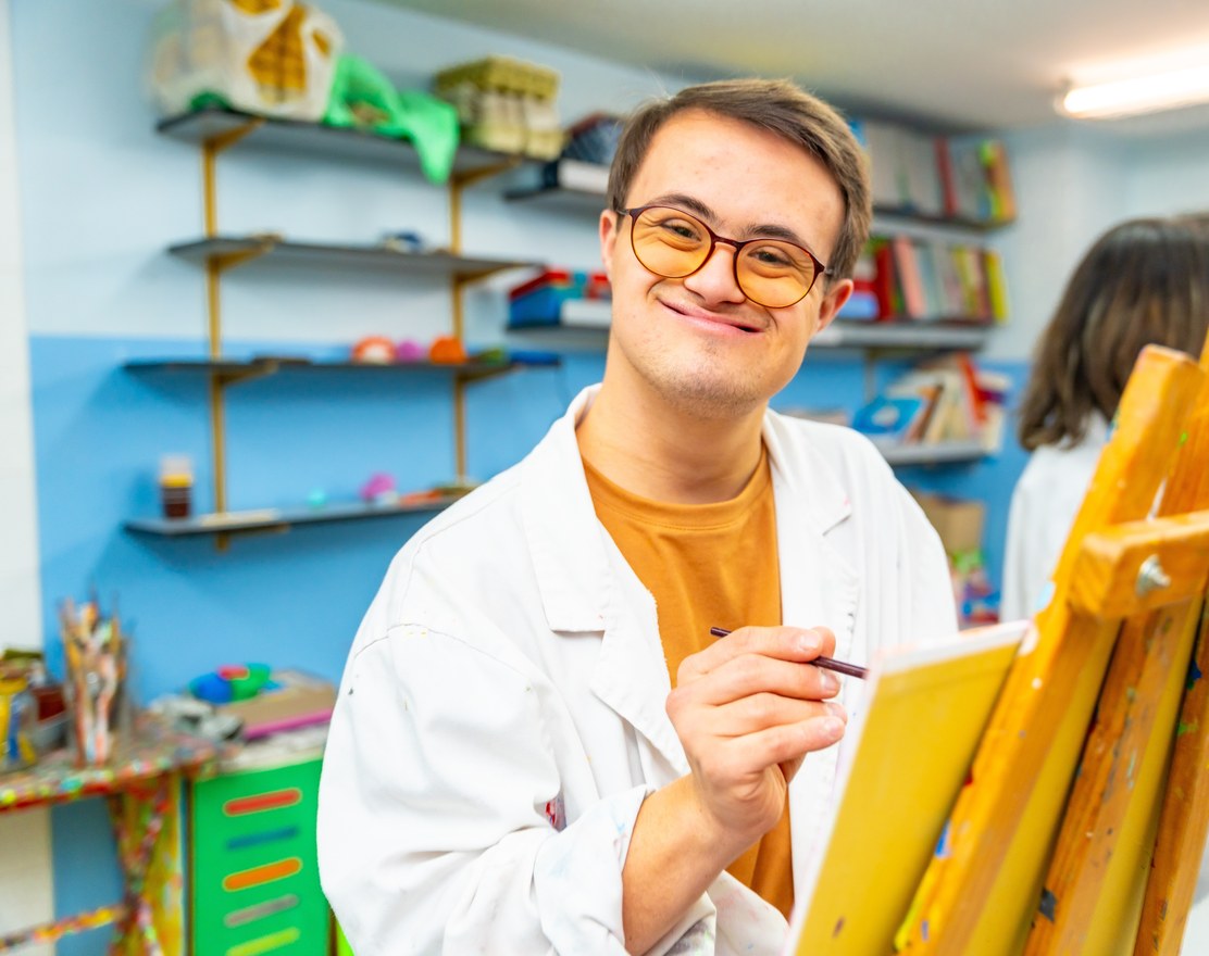 A young adult painting at an easel in a studio