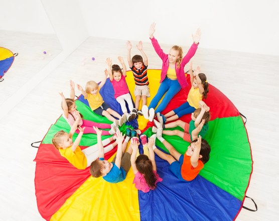 Children lying in a circle on a colorful parachute during a group session