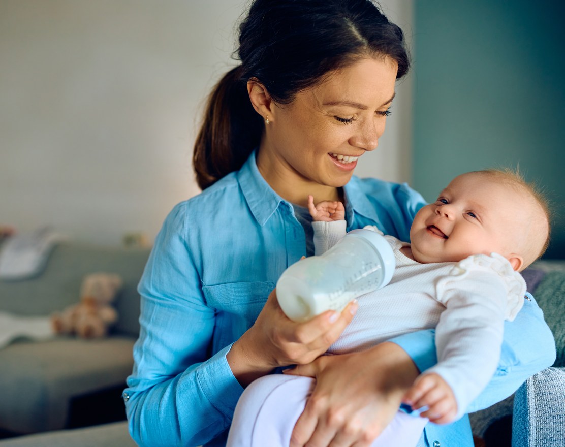 A mother bottle-feeding a smiling baby