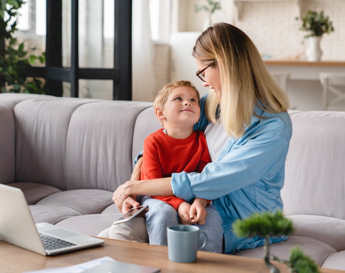 A mother sitting on a sofa talking with her young son