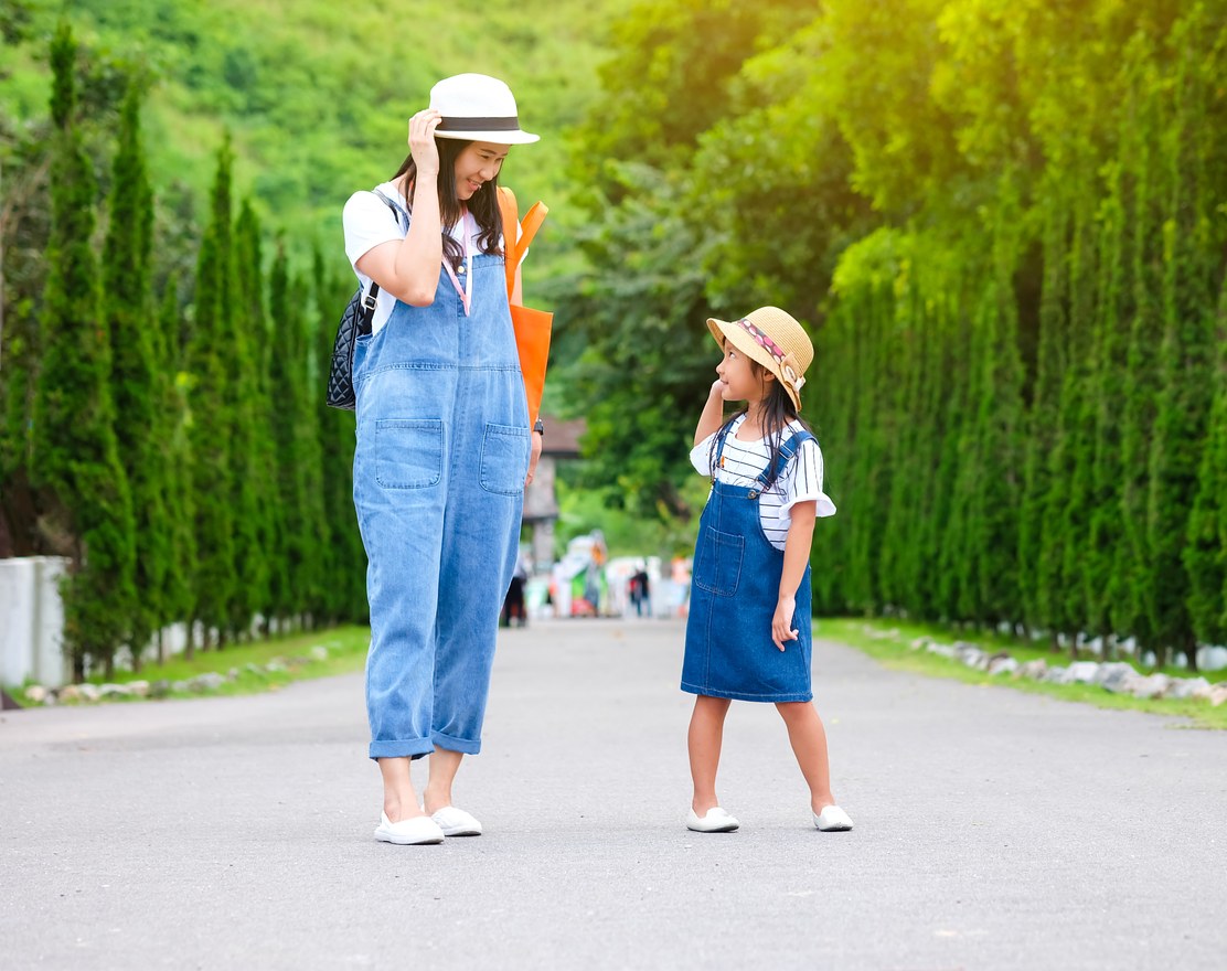 A mother and young daughter walking outdoors together