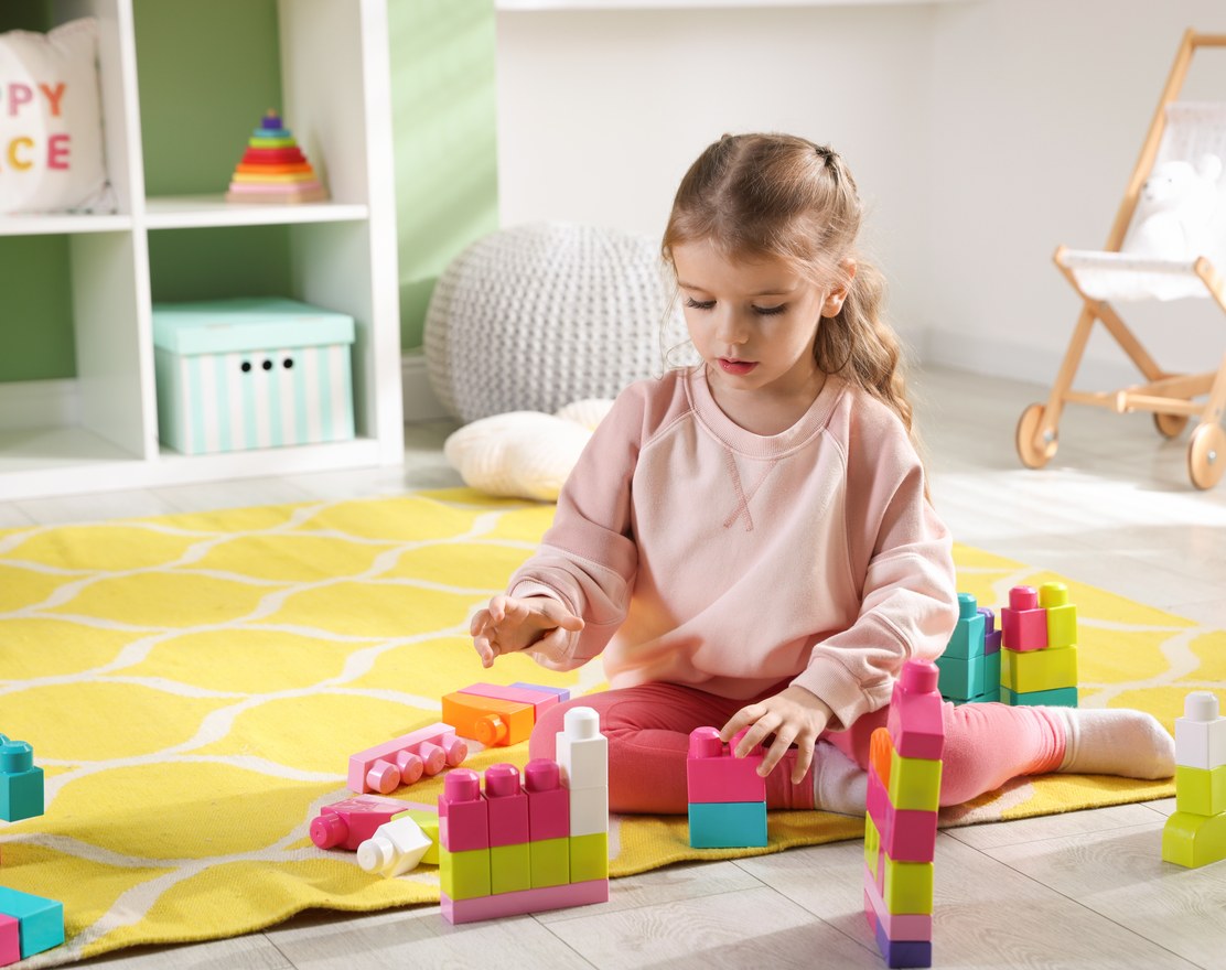 A young child concentrating while playing with building blocks