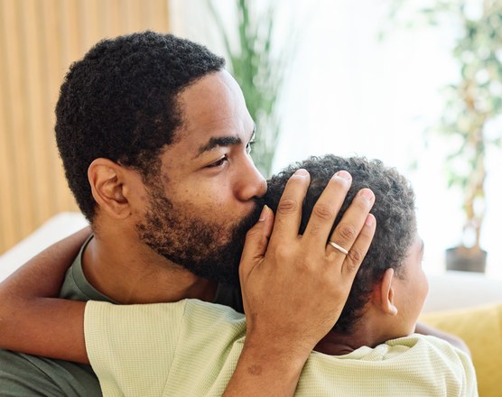 A father crouching to comfort an upset young child