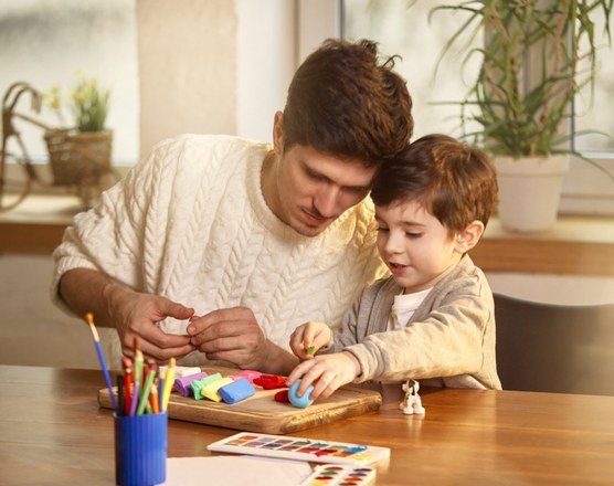 A father and toddler drawing together at a kitchen table
