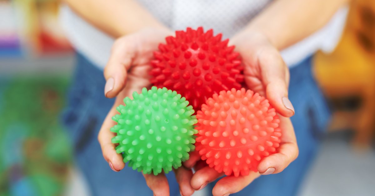 A child's hands cupped around three spiky textured sensory balls