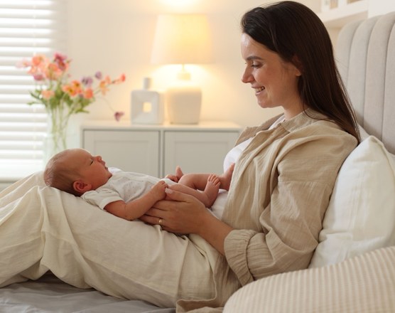 A mother sitting up in bed cradling her newborn