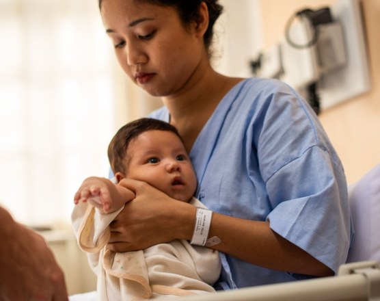 A mother in a hospital gown holding her newborn
