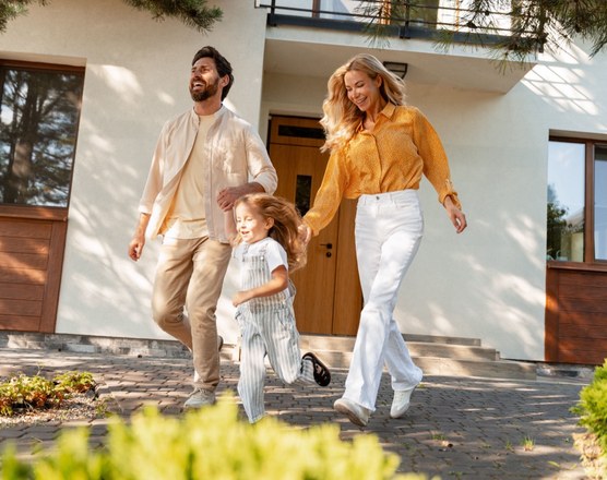 Two parents walking with their toddler outside a house