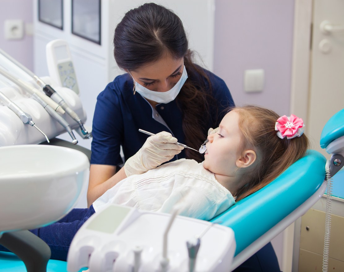 A dentist examining a young girl in a dental chair