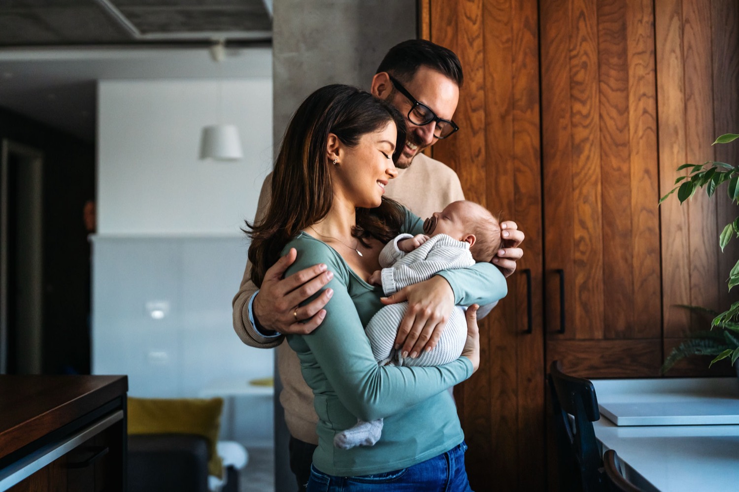 Two parents at home holding their sleeping newborn