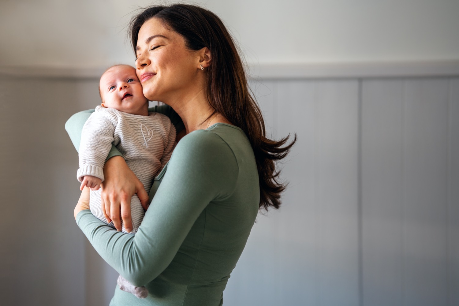 A mother holding her newborn baby against her shoulder