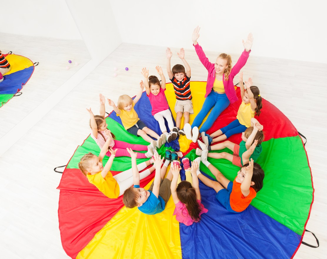 Children holding the edge of a play parachute in a circle