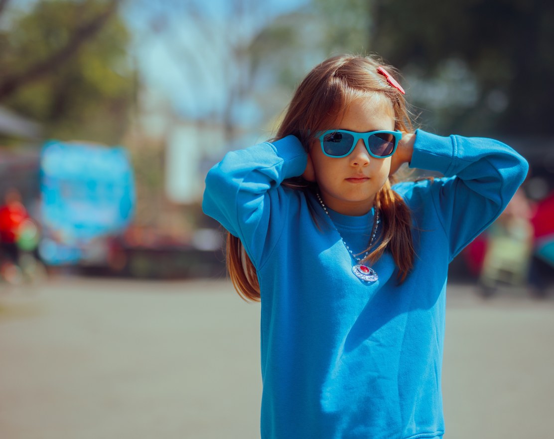 A girl outdoors covering her ears with both hands
