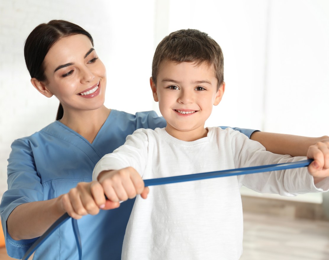 A therapist guiding a boy through resistance band exercises