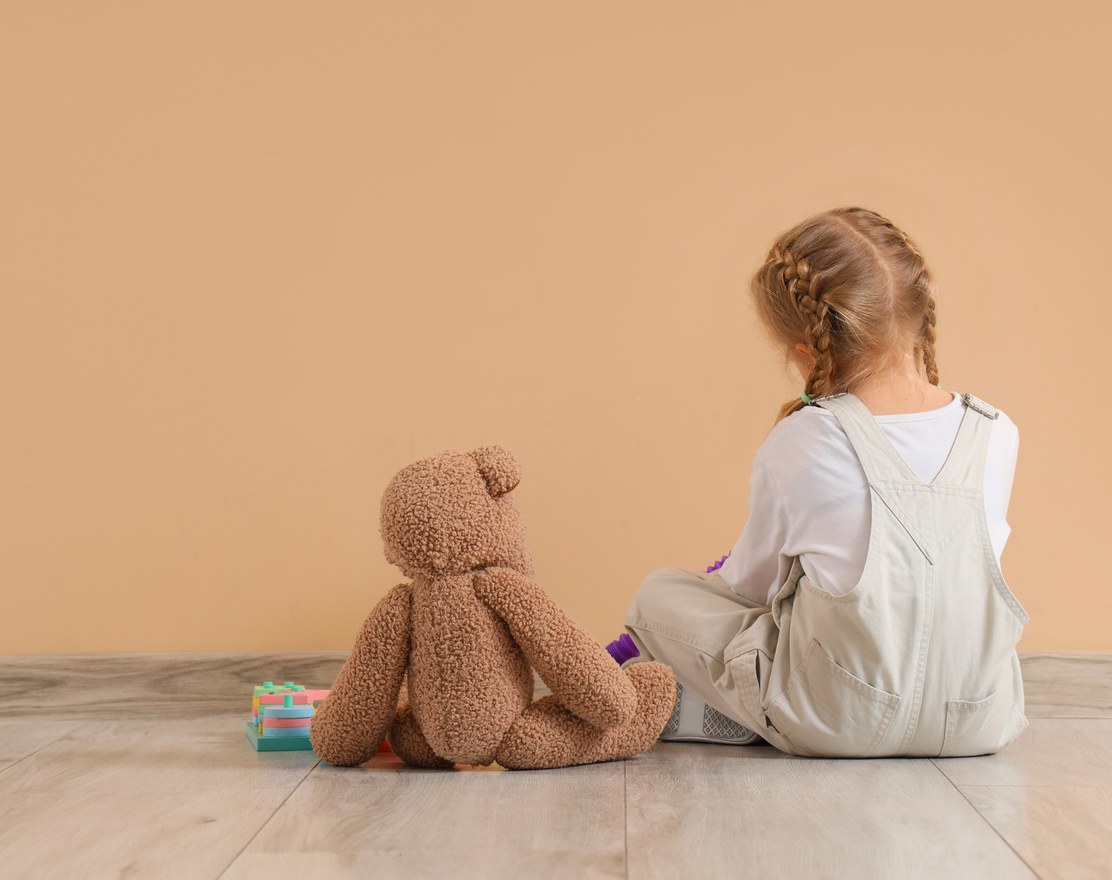 A girl sitting quietly holding a teddy bear