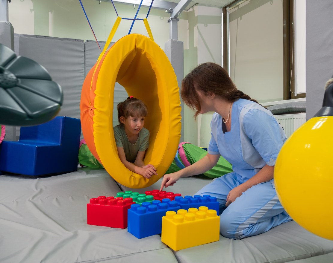 A child crawling through a padded tunnel in a therapy gym