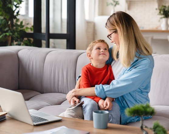 A mother sitting on a sofa talking with her young son