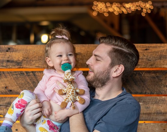 A father holding a toddler who is using a pacifier