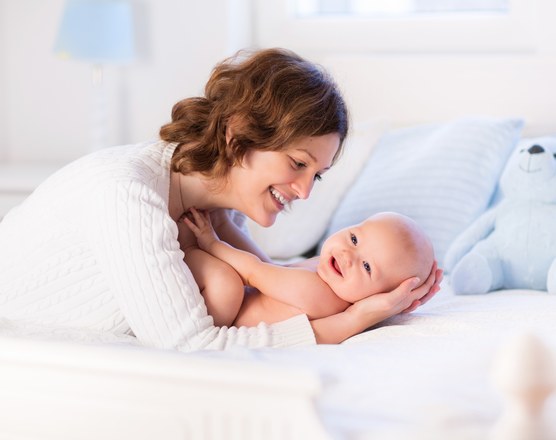 A mother lying in bed beside her newborn baby