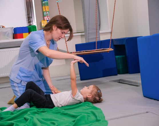 A therapist supporting a child on equipment in a pediatric sensory gym