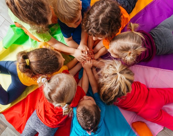 A group of children sitting in a circle on a colorful parachute