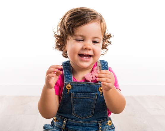 A laughing toddler in denim dungarees