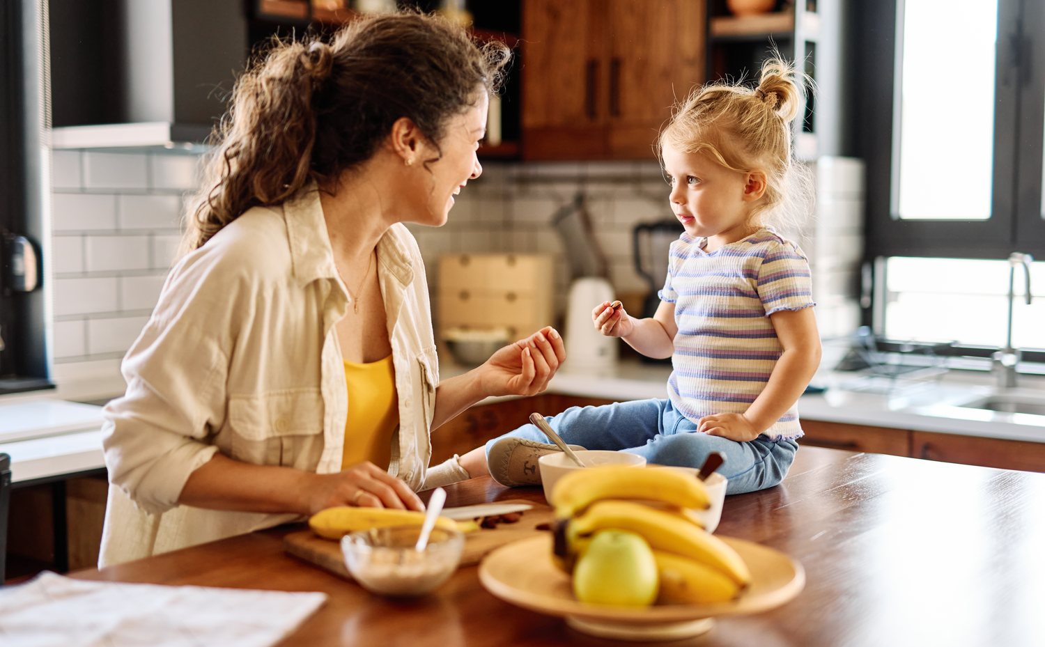 A mother and her toddler at the kitchen counter during breakfast