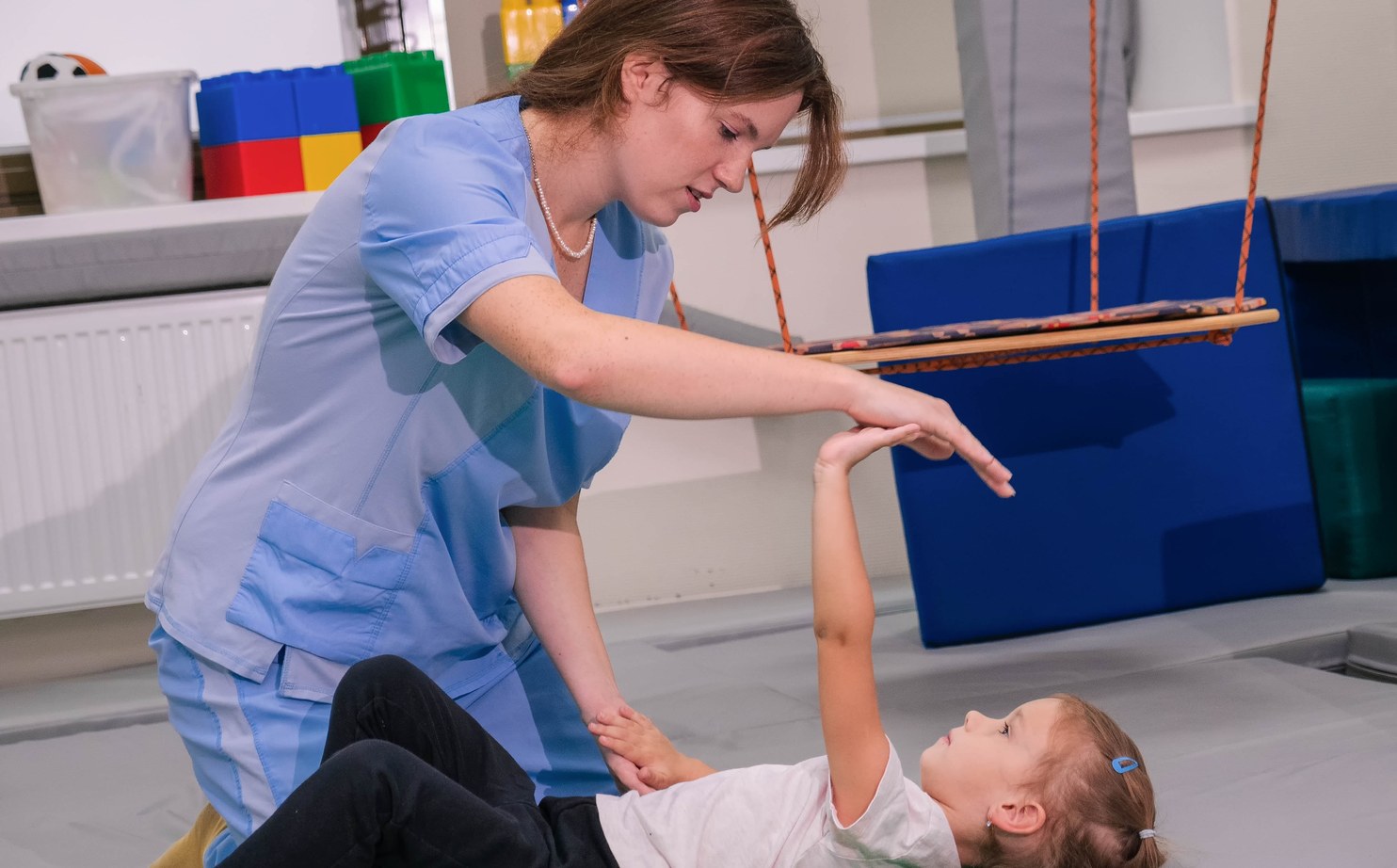 A therapist working with a child on a mat in a sensory gym