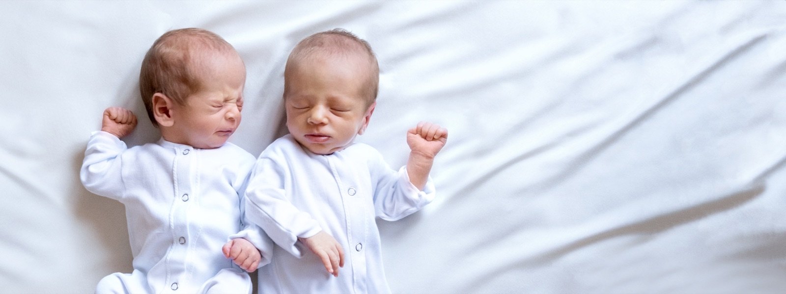 Two newborn twins sleeping side by side