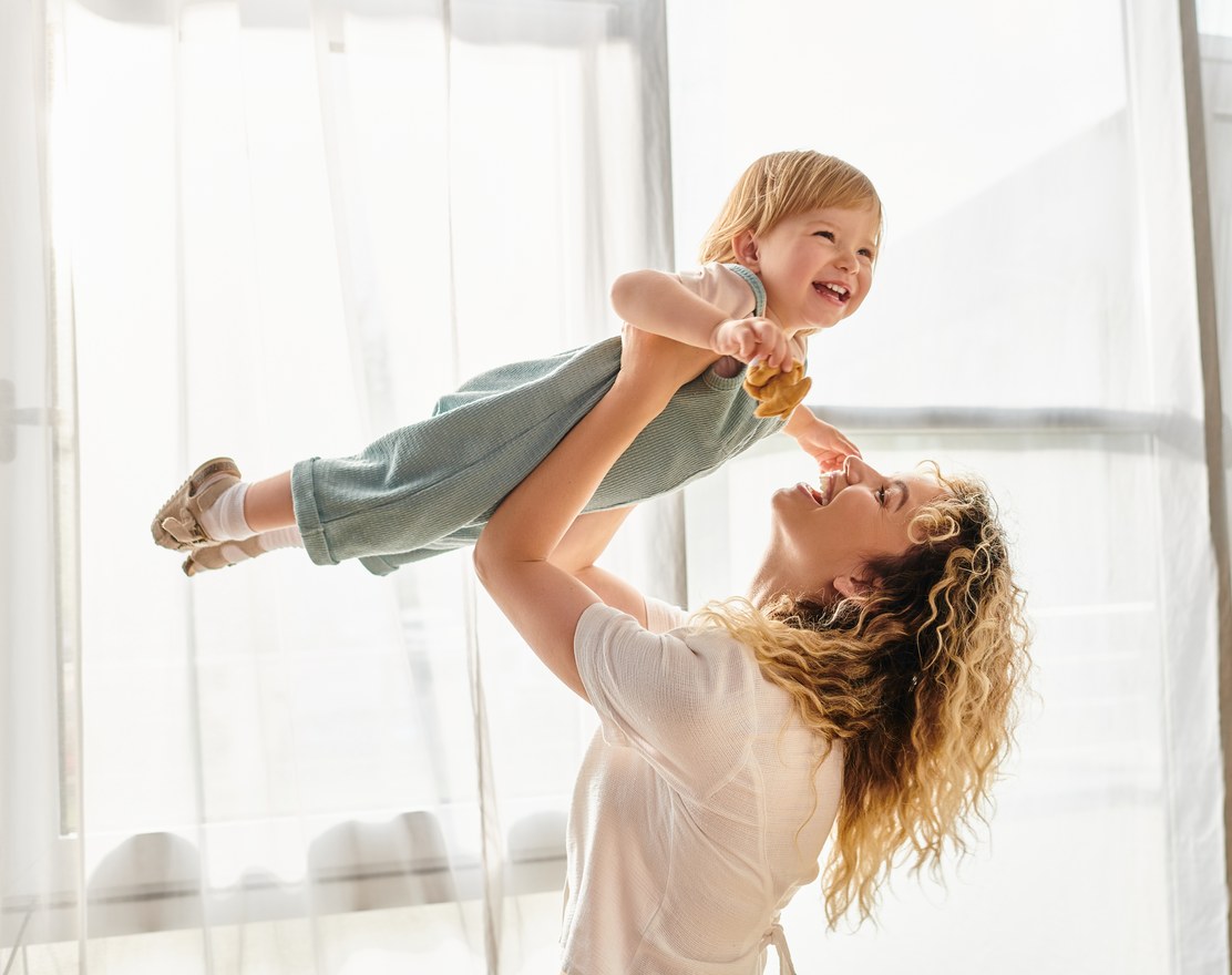 A parent lifting a laughing toddler into the air