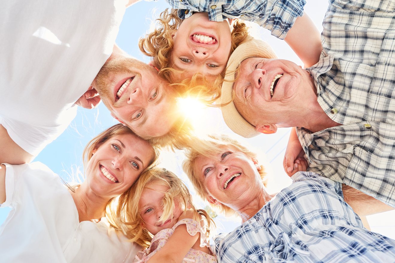 Three generations of a family, from a young girl to her grandparents, smiling down into the camera in a circle