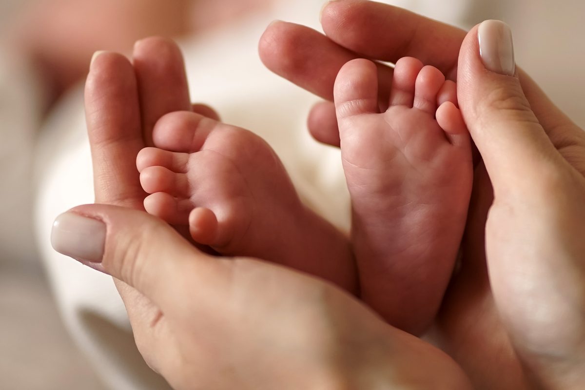 A parent&rsquo;s hands cradling a baby&rsquo;s bare feet