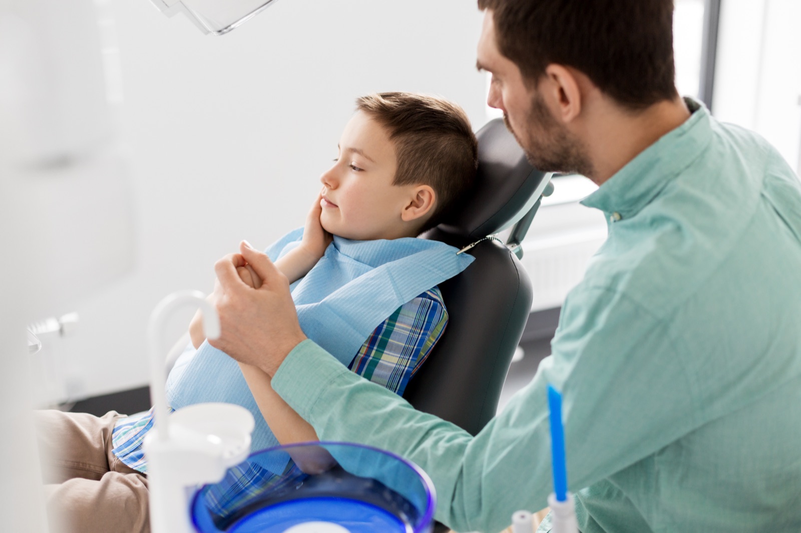 A child sitting calmly in a dental chair while a dentist talks with them
